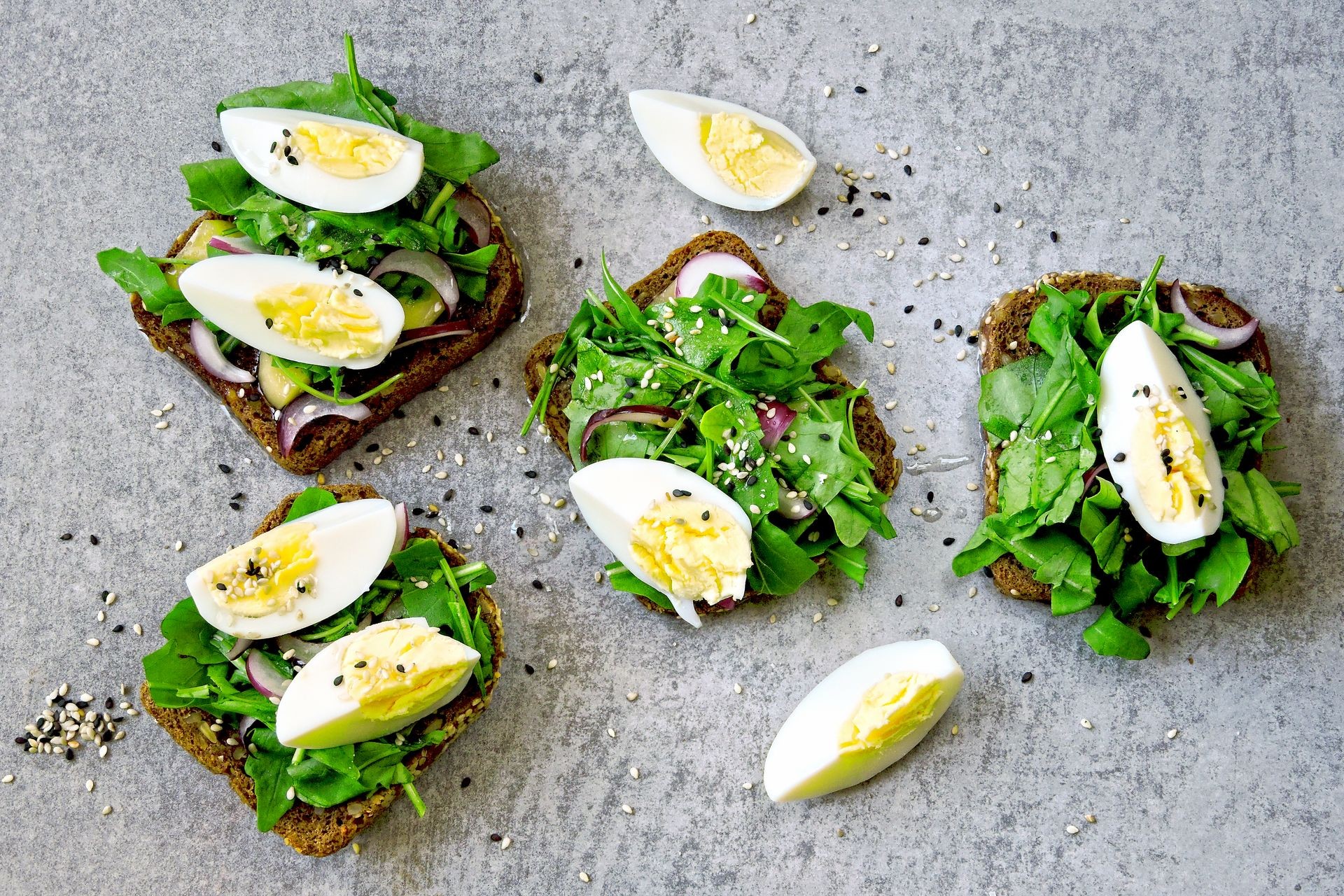 Healthy fitness toasts with arugula and egg. Useful snack lunch. Useful vegetarian toast. Open sandwiches rye bread with arugula, egg, blue onion and black and white sesame.